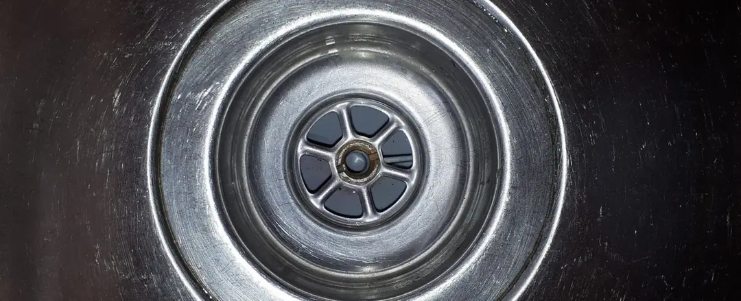 Close view of a stainless steel kitchen sink drain outlet