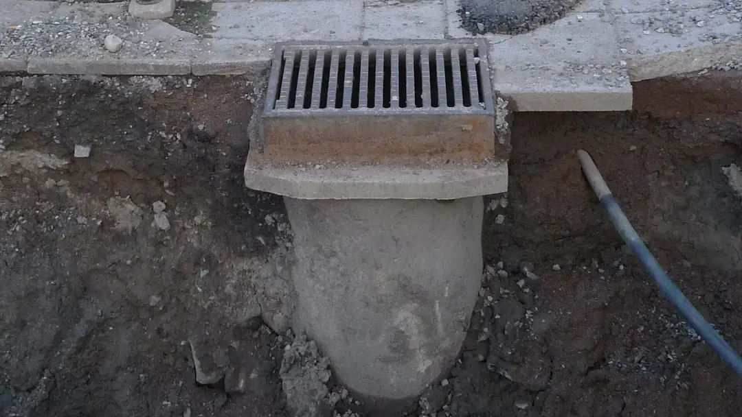 A street stormwater gully dug out to show the pipe beneath its grating
